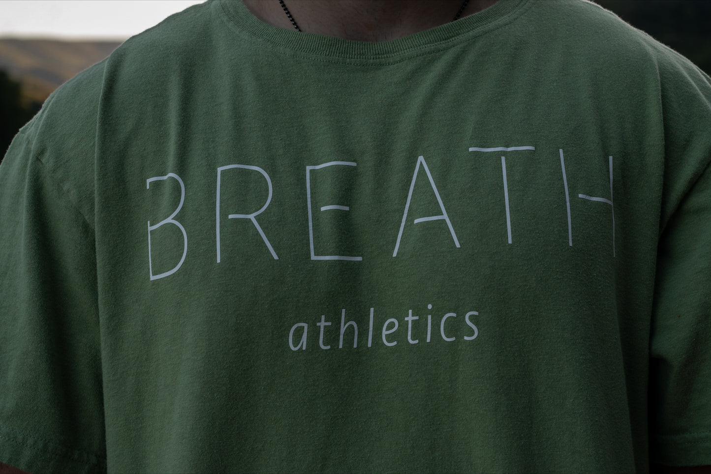 Close up Front of 100% organic cotton light mint green t-shirt with logo on the back and Breath across the front.