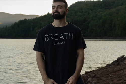 Front of Black Short Sleeve Organic Cotton T Shirt With the Word Breath Across the Chest.