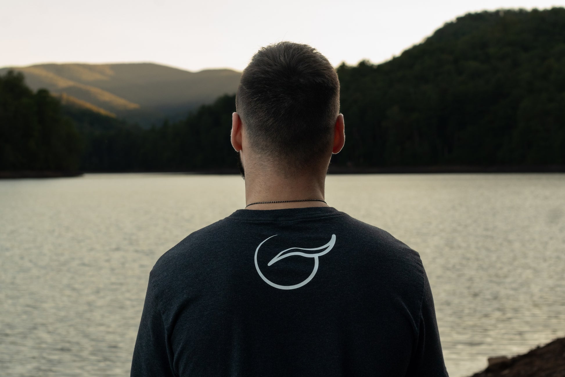 View of the Upper Shoulders of the Black Balance Short Sleeve 50/50 Up-Cycled Cotton Recycled Polyester Blended T Shirt  With the Breath Emblem Between the Shoulder Blades.