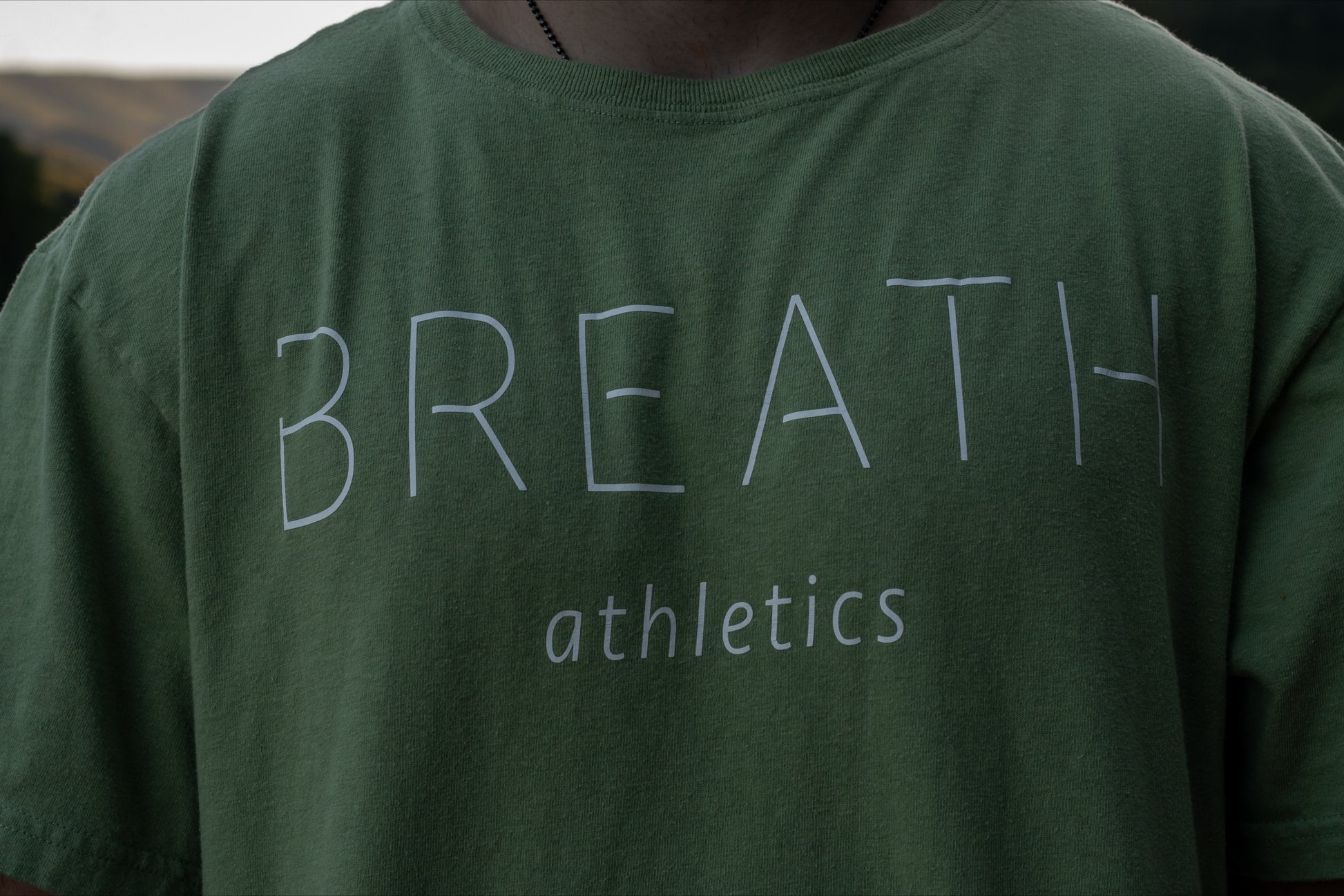Close up Front of 100% organic cotton light mint green t-shirt with logo on the back and Breath across the front.