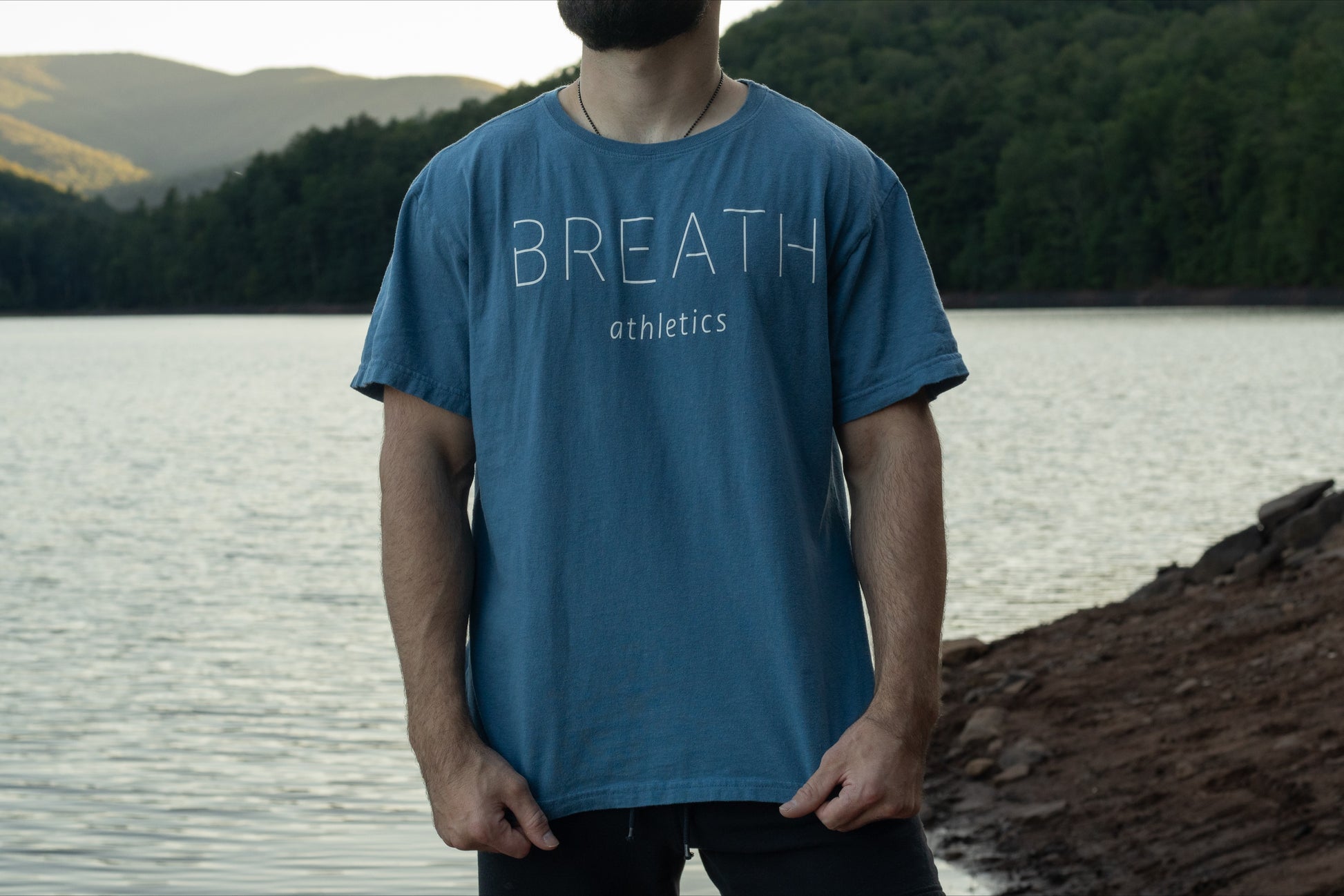 Front of light blue t shirt made from 100% Organic Cotton displaying the Breath brand name across the front with the logo on the back.