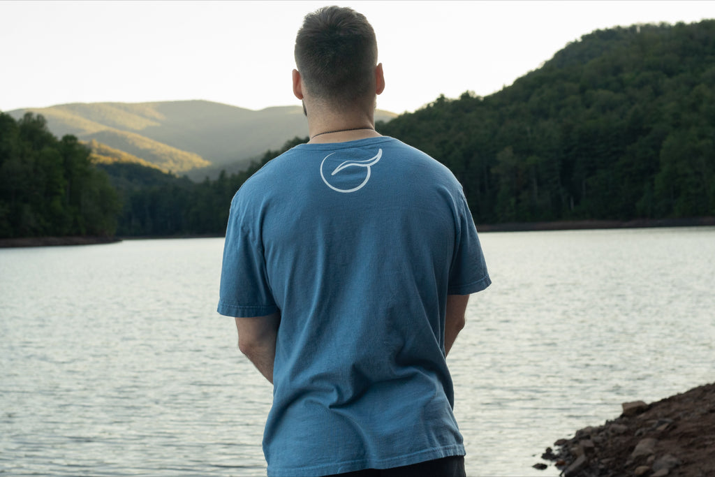 Back of light blue t shirt made from 100% Organic Cotton displaying the Breath brand name across the front with the logo on the back.
