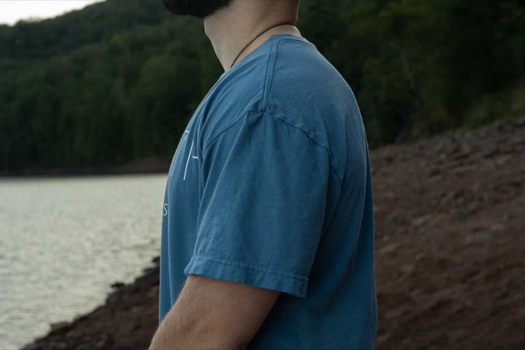 Side View of light blue t shirt made from 100% Organic Cotton displaying the Breath brand name across the front with the logo on the back.