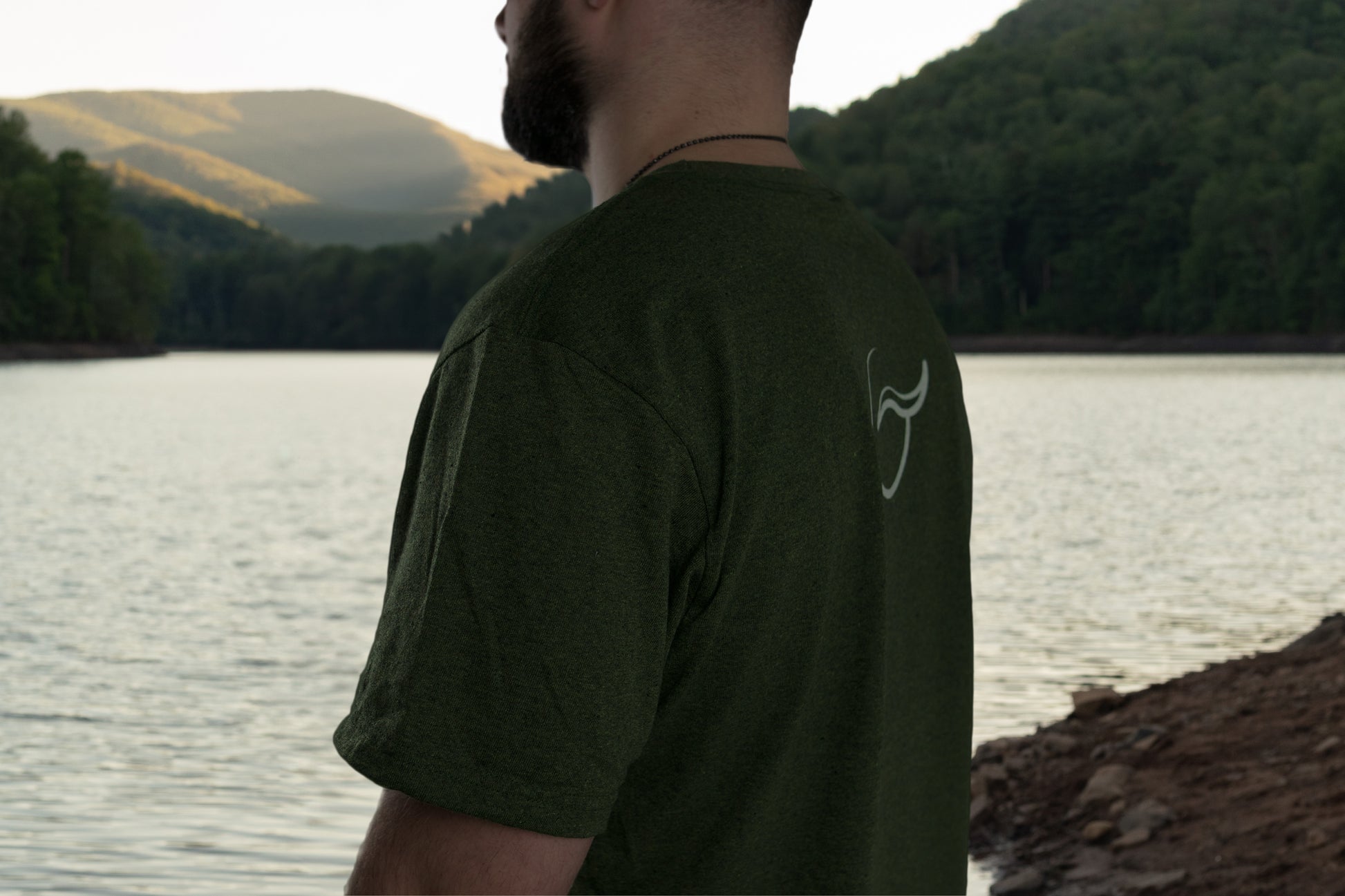 over the shoulder picture of the green short sleeve t shirt made from up-cycled cotton and recycled polyester with the logo between the shoulder blades.
